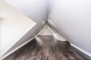 Bonus room with lofted ceiling and dark wood finished floors