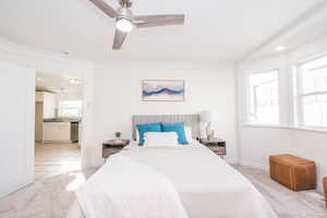 Bedroom featuring light carpet, ceiling fan, connected bathroom, and crown molding