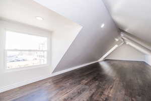 Additional living space featuring dark wood finished floors and vaulted ceiling