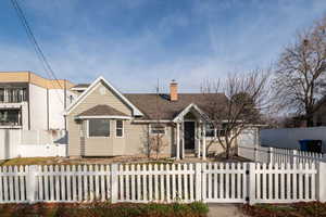 View of front of house with a chimney, roof with shingles, and a fenced front yard