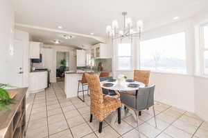 Dining space with light tile patterned floors, a chandelier, and recessed lighting
