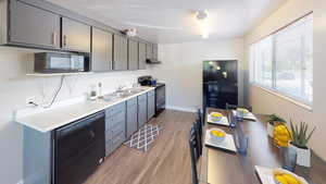 Kitchen featuring black appliances, light countertops, light wood-style floors, and gray cabinets