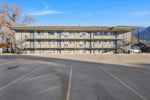 View of apartment building / complex with stairs and uncovered parking