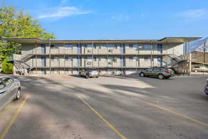 View of apartment building / complex featuring stairs and uncovered parking
