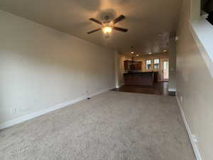 Unfurnished living room with a ceiling fan and dark carpet