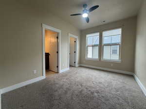 Unfurnished bedroom featuring a spacious closet, light colored carpet, ceiling fan, and a textured ceiling
