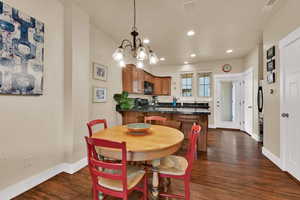 Dining space with dark wood-type flooring, recessed lighting, and a chandelier