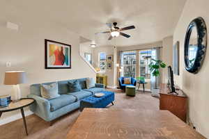 Carpeted living area with a ceiling fan and baseboards