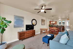 Living area with ceiling fan, light colored carpet, recessed lighting, and a chandelier