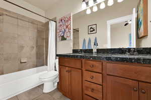 Bathroom with double vanity, shower / bath combo with shower curtain, and light tile patterned floors