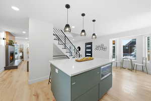 Kitchen featuring light wood finished floors, hanging light fixtures, a center island and recessed lighting