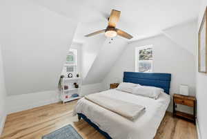 Bedroom with light wood finished floors, lofted ceiling, and ceiling fan