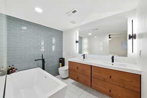 Full bath featuring a freestanding tub, double vanity, light tile patterned flooring and recessed lighting