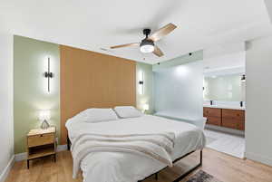 Bedroom with light wood finished floors, a ceiling fan, and ensuite bath
