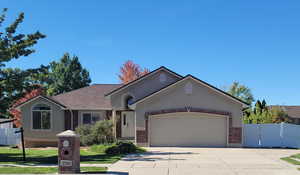 Ranch-style house with brick siding, driveway, a garage, and stucco siding