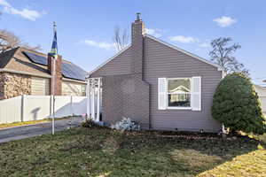 View of property exterior featuring brick siding and a chimney