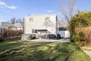 Back of property with a fenced backyard, a hot tub, and a patio area