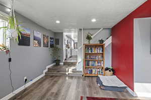 Hallway featuring stairway, wood finished floors, a textured ceiling, and recessed lighting