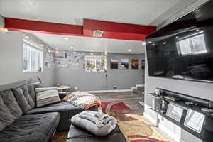 Living area featuring plenty of natural light, wood finished floors, a textured ceiling, stairway, and recessed lighting