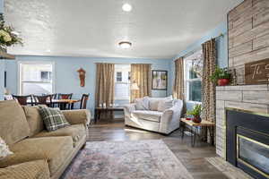 Living area featuring a textured ceiling, plenty of natural light, a large fireplace, dark wood-style floors, and recessed lighting