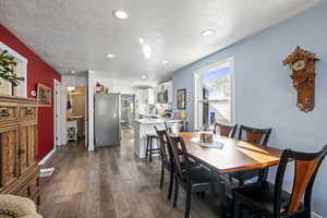 Dining area with recessed lighting, dark wood-style floors, and a textured ceiling