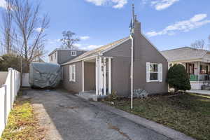 View of property exterior with a chimney, a shingled roof, and driveway