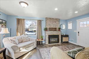 Living area featuring a textured ceiling, a fireplace, healthy amount of natural light, wood finished floors, and recessed lighting