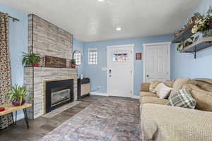 Living area featuring a large fireplace, a textured ceiling, dark wood-style flooring, and recessed lighting