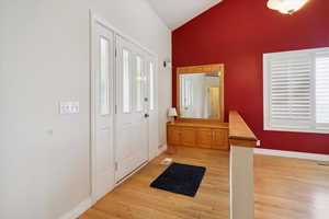 Entrance foyer with vaulted ceiling and light wood-style floors