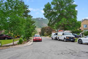 View of asphalt street featuring a mountain view, curbs, and sidewalks