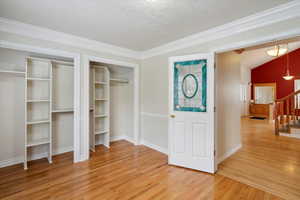 Office with light wood-type flooring, stairs, a textured ceiling, and crown molding