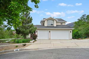 Traditional-style house with stucco siding, driveway, and roof with shingles