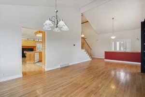 Living room with light wood finished floors, beam ceiling, high vaulted ceiling, stairway, and a premium fireplace