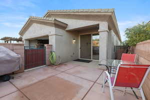 Rear view of house with a gate, a patio area, stucco siding, and outdoor dining area