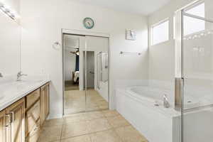 Bathroom featuring a bath, double vanity, a stall shower, light tile patterned flooring, and ensuite bathroom
