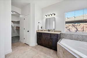 Full bathroom featuring vanity, a bath, and a spacious closet