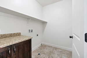 Washroom featuring hookup for a washing machine, hookup for an electric dryer, light tile patterned flooring, and cabinet space