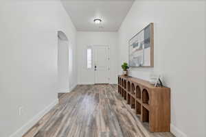 Foyer with arched walkways and light wood finished floors