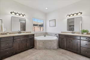 Full bath featuring two vanities and a garden tub