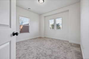 Unfurnished room with light colored carpet and healthy amount of natural light