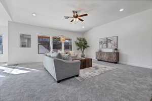 Carpeted living area featuring lofted ceiling, ceiling fan, and recessed lighting