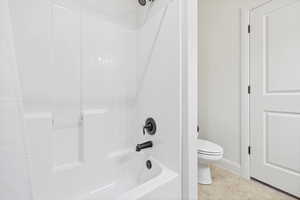 Bathroom with bathing tub / shower combination and light tile patterned floors