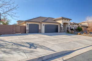 View of front facade with an attached garage, stucco siding, concrete driveway, and a gate