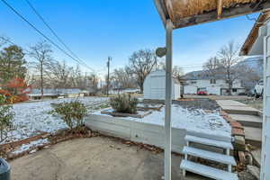 Snow covered patio with a shed and a vegetable garden