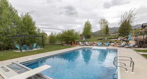 View of swimming pool featuring a patio area, a fenced backyard, a diving board, and an outdoor fire pit