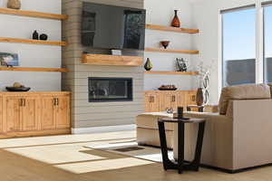Living room with light wood-style flooring and a glass covered fireplace