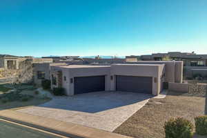Pueblo-style house with stucco siding, a garage, driveway, and a residential view