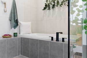 Bathroom featuring a stall shower, a garden tub, and tile walls