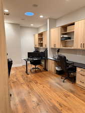 Office area featuring built in study area, light wood finished floors, and recessed lighting