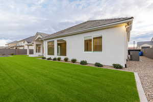 Back of house with stucco siding and a tile roof